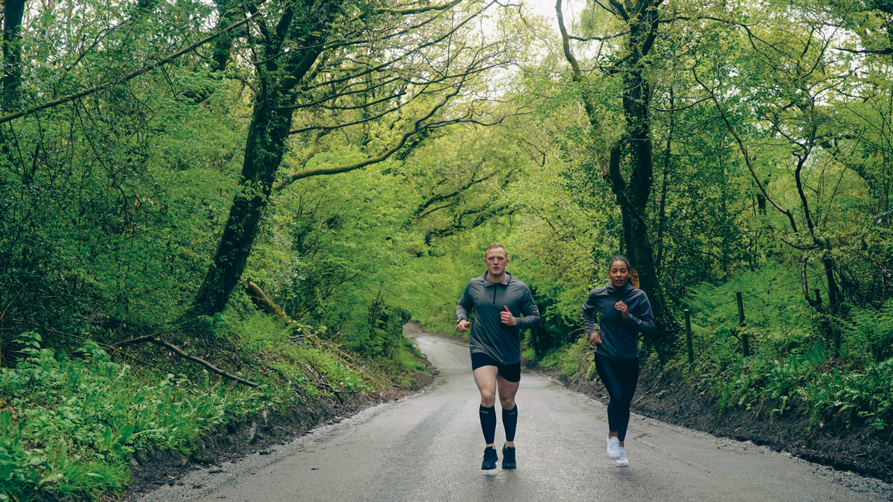 Two Runners Male and Female running through woods in CRX Compression Wear
